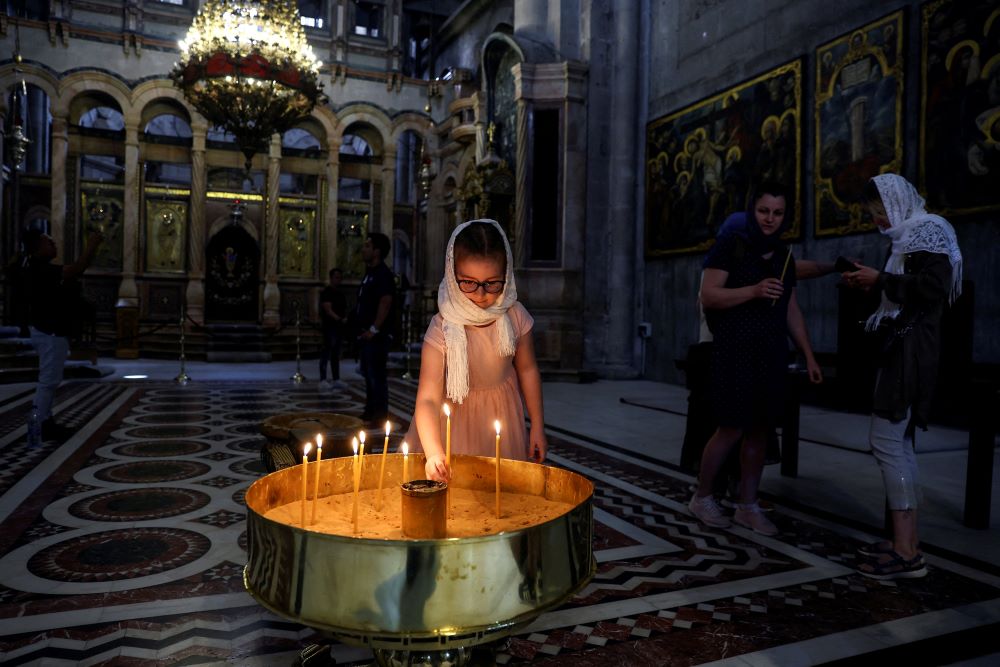 A girl places a candle in the Church of the Holy Sepulcher in Jerusalem's Old City on April 11, 2022.